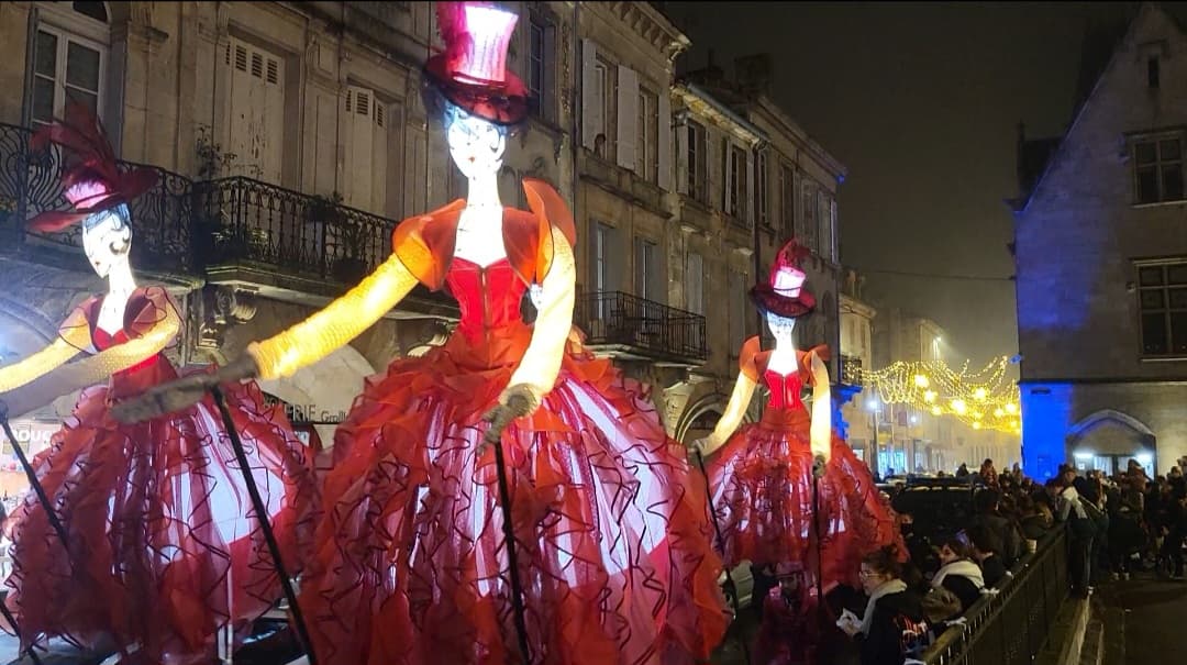 Marionnettes lumineuses en robes rouges dans une rue de festival, la nuit